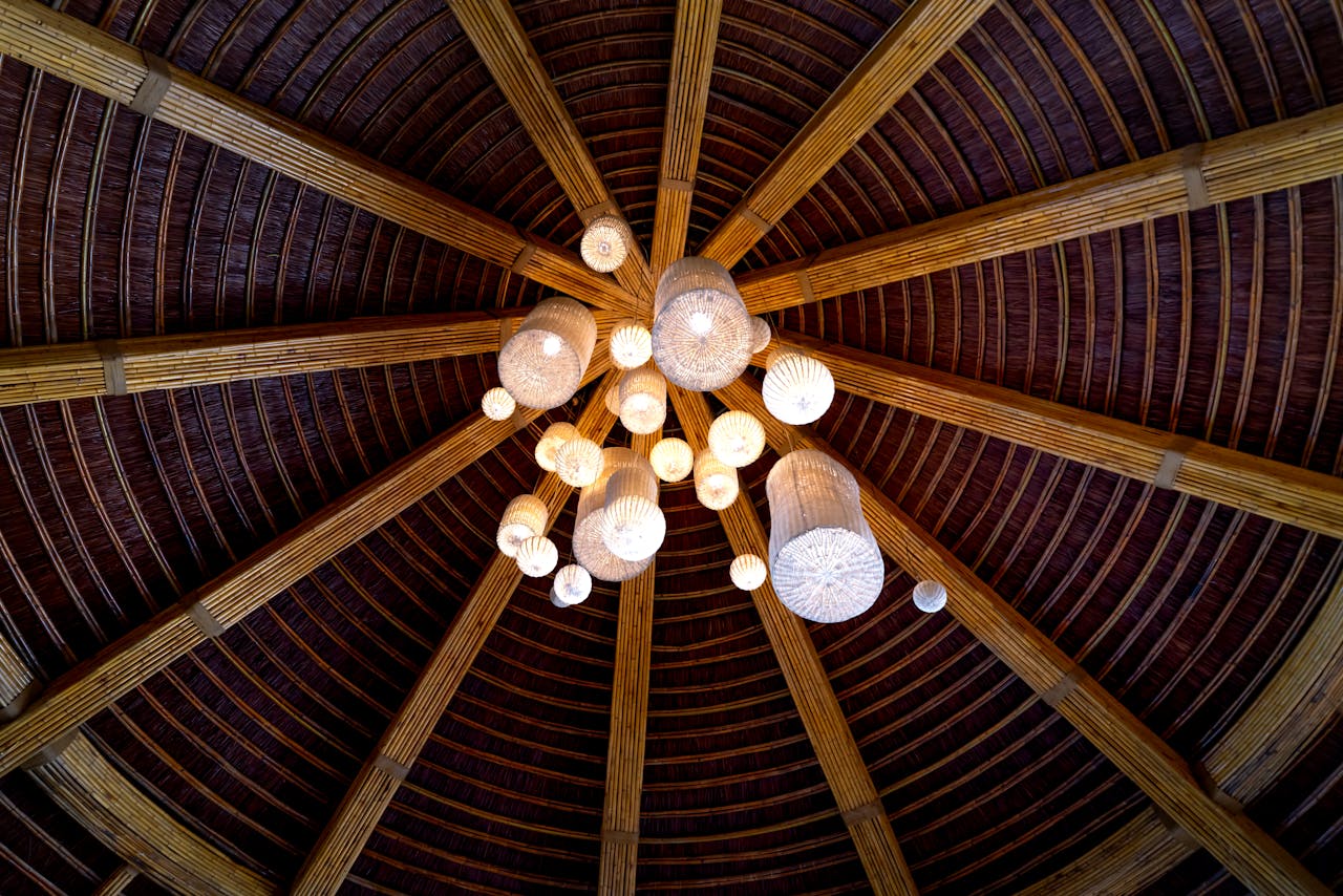 A stunning bamboo ceiling showcasing a central chandelier with glowing lamps, emphasizing a modern interior design.