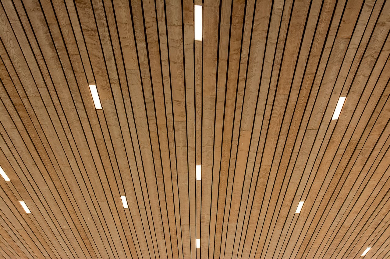 An abstract view of a wooden ceiling featuring linear lights creating a modern design.