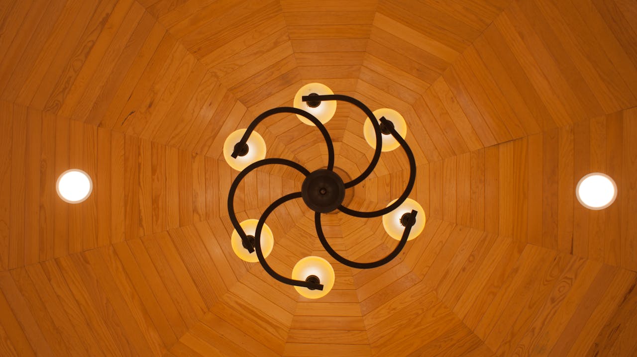View of an artistic chandelier on a warm, wooden ceiling.